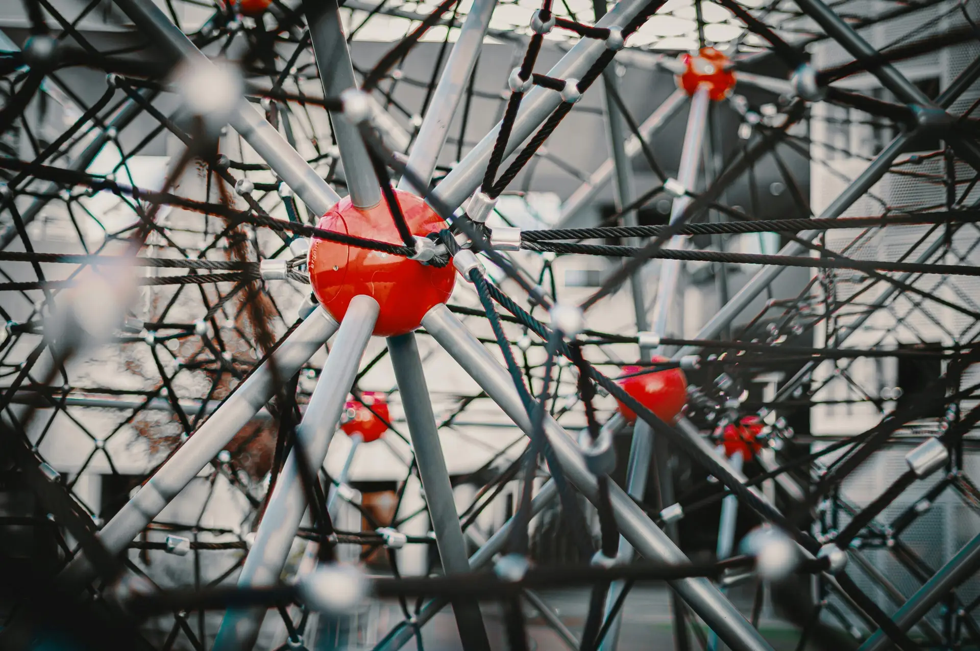 Colorful metallic construction with straight beams and red spheres on pavement in town
