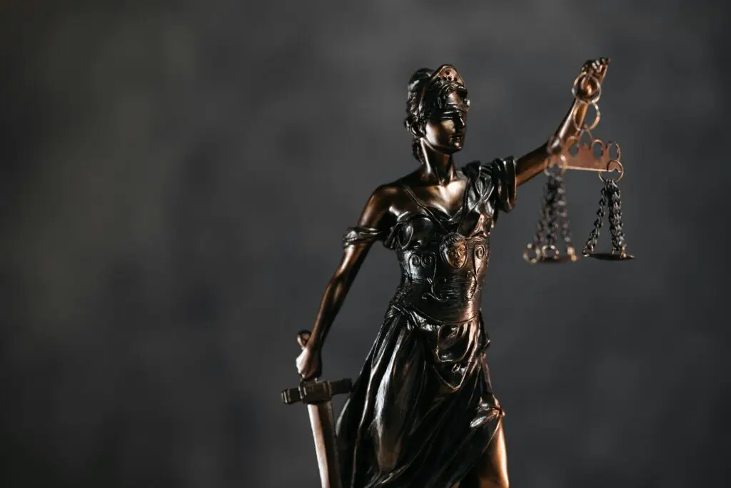 Detailed bronze Lady Justice statue with scales and sword against a dark background, symbolizing law and justice.